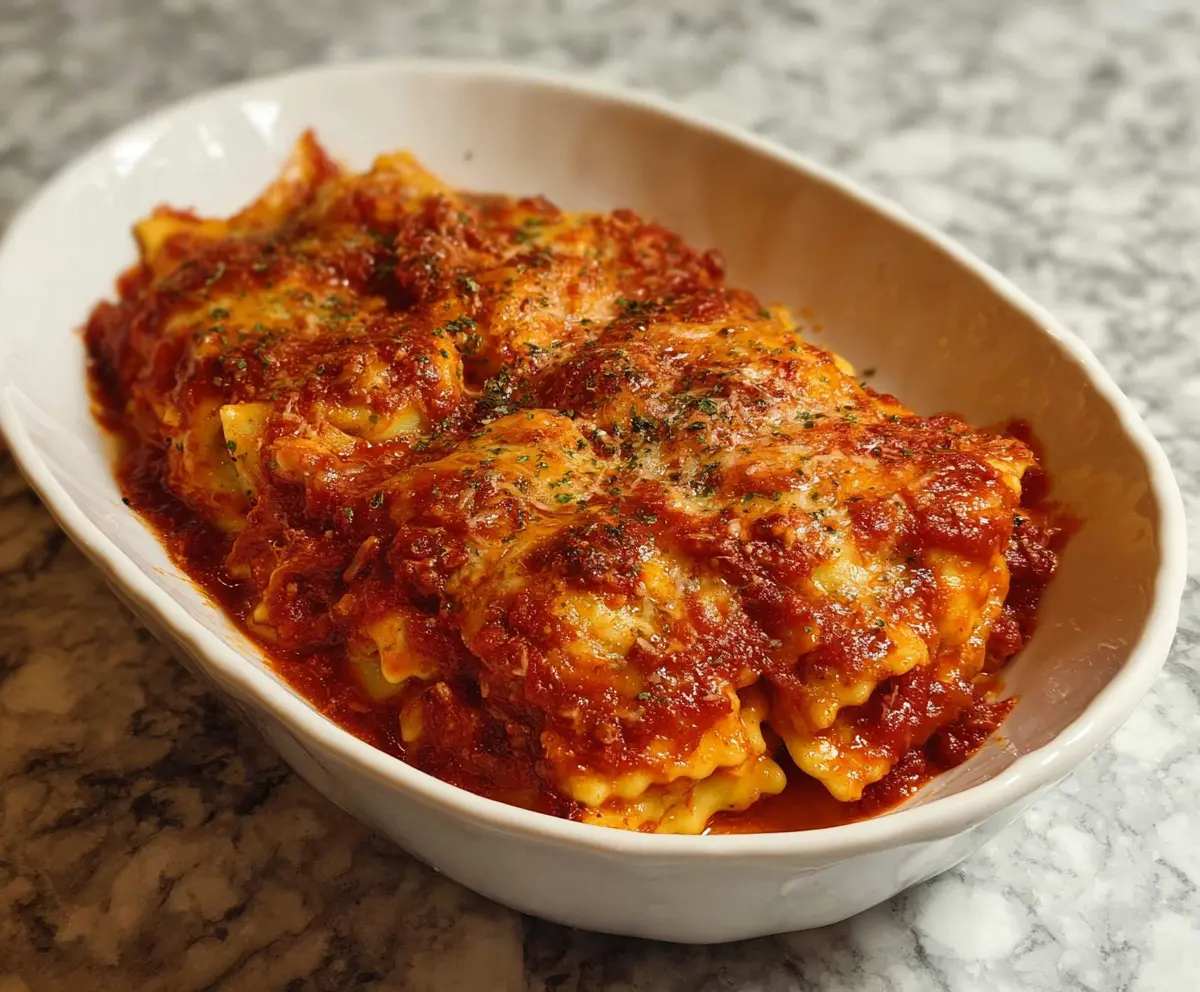 Delicious 3 Ingredient Ravioli Bake, also known as Lazy Lasagna, served in a baking dish with melted cheese and fresh herbs.