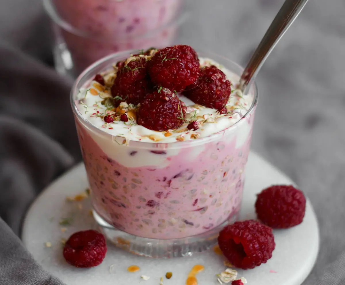 Delicious raspberry overnight oats in a glass jar topped with fresh raspberries and chia seeds.